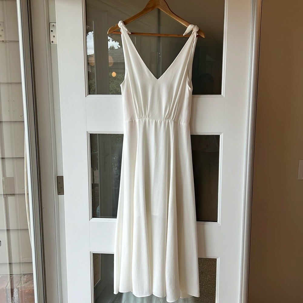 White midi length crepe dress with tied straps.